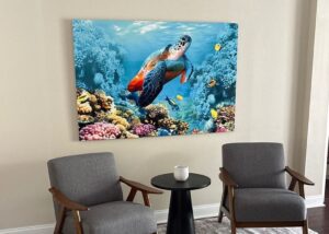 Sea turtle and coral wall art displayed above two gray chairs and a small round table