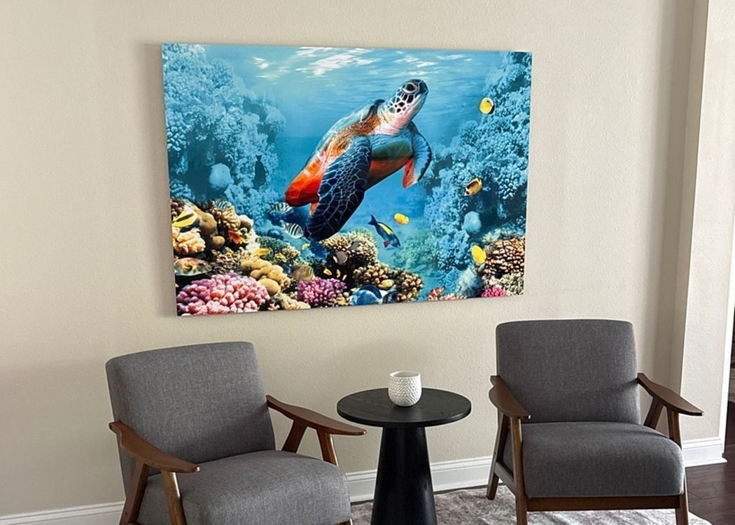 Sea turtle and coral wall art displayed above two gray chairs and a small round table