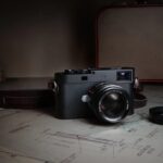 Leica Summicron-M 66 f/2 mounted on an M camera beside technical drawings