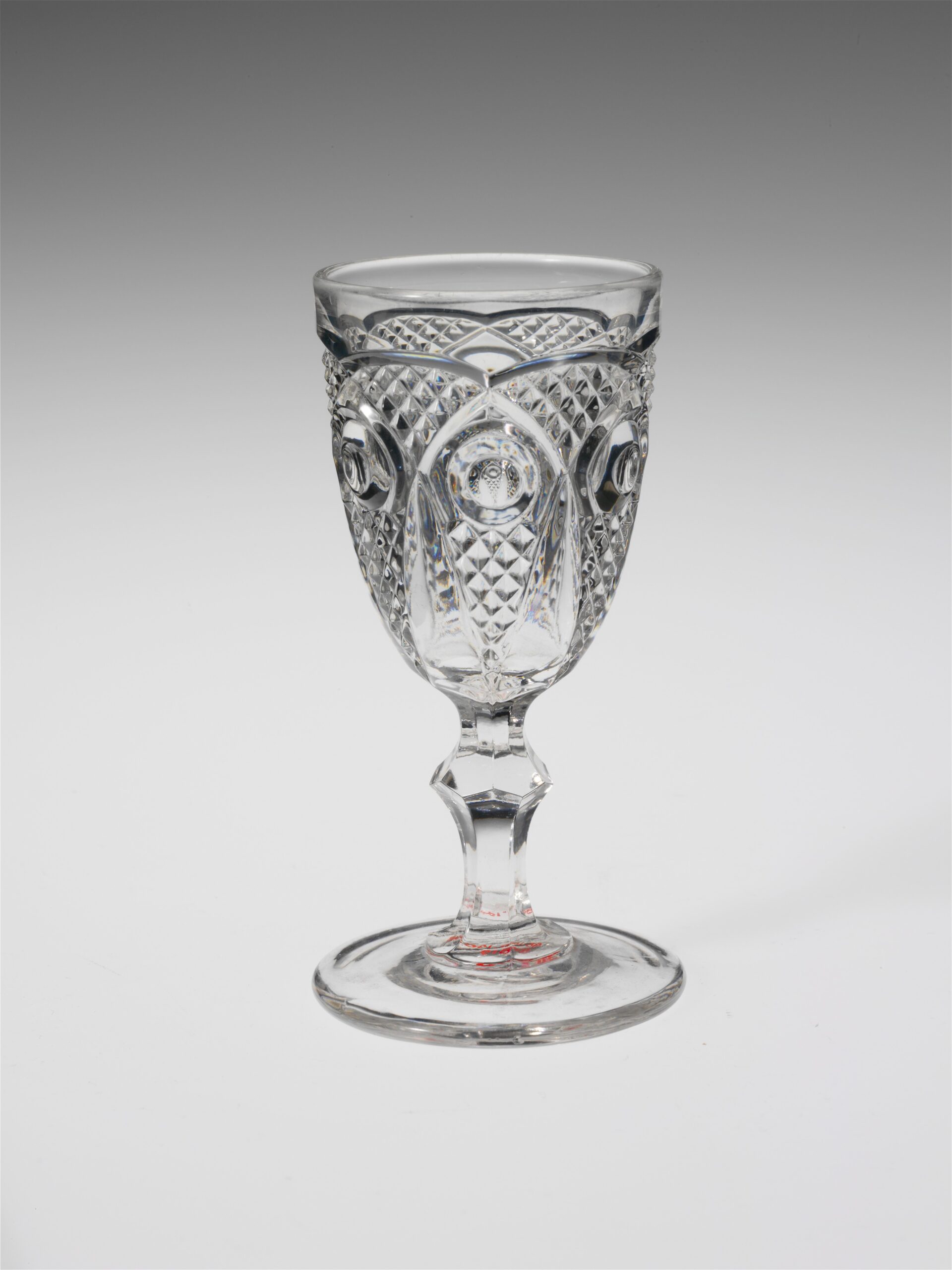 Historic stemmed wine glass photographed against a plain background.